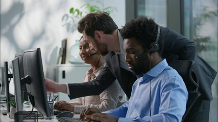 Multiethnic callcenter smiling Caucasian boss explain pointing pc monitor Indian woman employee office teamwork business call center customer support training African man headset helpline hotline desk - Powered by Adobe
