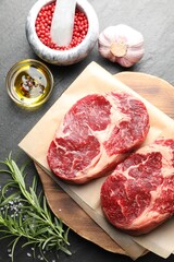 Pieces of raw beef meat and spices on black table, flat lay