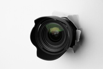 Hidden camera lens through torn hole in white paper