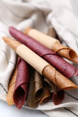 Tasty fruit leather rolls on white table, closeup