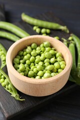 Fresh ripe green peas on black wooden table, closeup