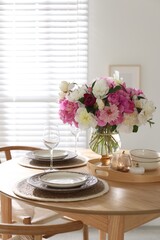 Beautiful table setting with bouquet of peonies in dining room