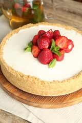 Tasty cheesecake with strawberries and mint on wooden table, closeup