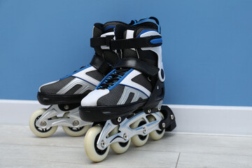 Pair of roller skates on floor near light blue wall