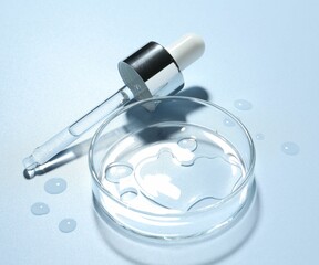 Cosmetic product in Petri dish and dropper on light blue background, closeup