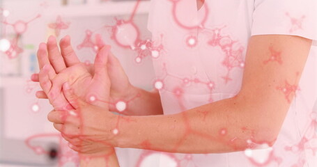 Showing uniformed therapist hands holding patient hand and wrist in clinic, with molecular overlay