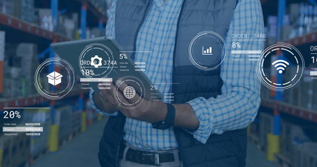 Supervisor holding tablet and viewing holographic data in warehouse with shelves, boxes and pallets