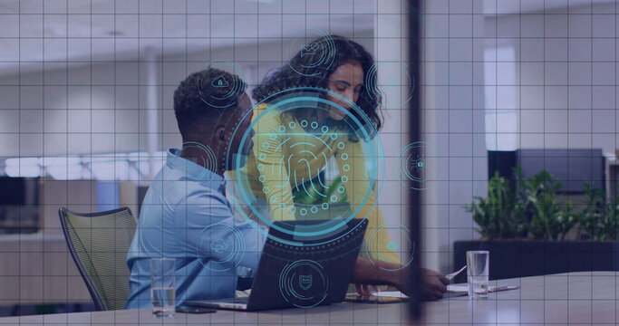 Leaning woman pointing and man examining biometric overlay on laptop at conference table in office
