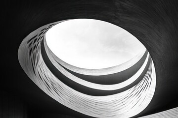 Abstract black and white spiral architectural structure with curved bands forming an open circular skylight revealing the sky