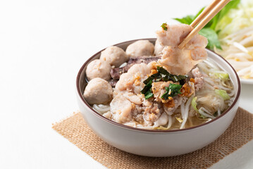 Thai noodles soup with sliced pork, minced pork, meatball and liver in a bowl eating with fresh vegetables on white background, Traditional Thai street food