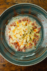 Gourmet Tiradito with a modern fusion twist, a Peruvian-style raw fish dish similar to ceviche, served with crumbled chorizo and paprika in a creamy leche de tigre sauce in a rustic bowl.