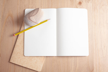 Cuaderno abierto con lápiz y piedra sobre mesa de madera