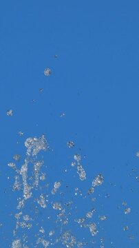 青空を背景に飛び散る噴水の飛沫の亜アップ