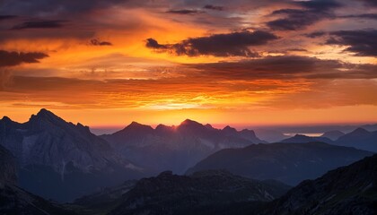 majestic sunset over mountain ranges with dramatic clouds and warm light in the evening sky