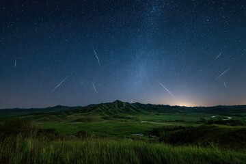 Night sky panorama showcasing a meteor shower over rolling green hills and a valley.  The Milky Way is subtly visible