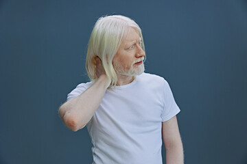 Portrait of a thoughtful elderly man with long white hair against a soft blue background, feeling...