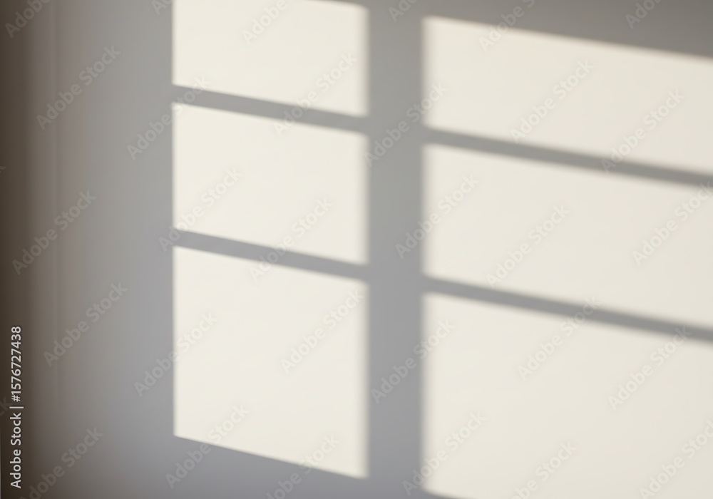 Poster a wall with a window's shadow, creating geometric shapes and light patterns.
