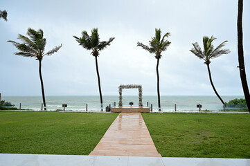 outdoor wedding ceremony altar overlooking the sea, surrounded by palm trees and with a central...