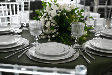 table set in ballroom, elegant wedding reception table with candlesticks, luxury dinner arrangement with floral centerpiece, formal dining table with clear chairs and silver candelabras
