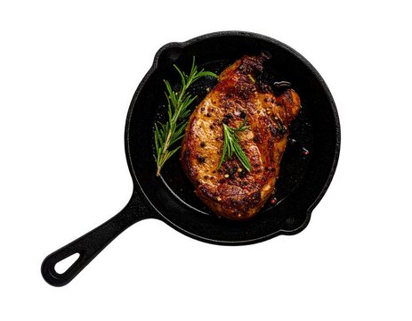 Grilled pork chop in cast iron skillet with rosemary Overhead shot meat