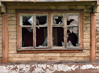 Broken glass window of old two-story wooden abandoned building