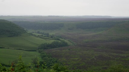 Heather moorland and green fields forming rolling hills in North York Moors National Park, England, United Kingdom