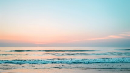 Fototapeta premium Soft pastel sunset painting the sky over a calm ocean beach, with gentle waves lapping the shore. The sky blends hues of pink, blue, and purple, while the water mirrors the serene colors, 