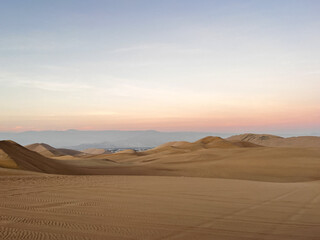 Endless view of sand dunes in desert landscape at sunrise sunset hour. Arid Landscape scenery Huacachina, Ica, Peru. Tourist destination for extreme sports, adventure, journey and travel concept.