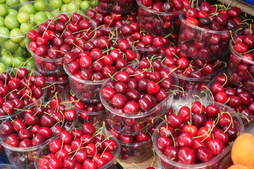 Fresh cherries and green fruits at a market stall