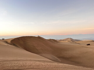 Beautiful range of sand dunes in desert at sunrise sunset hour. Arid Landscape scenery Huacachina, Ica, Peru. Tourist destination for extreme sports, adventure, journey and travel concept.