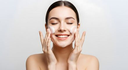 Smiling woman applying face wash with eyes closed
