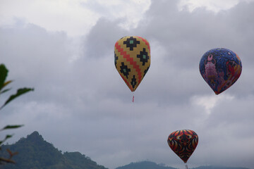 Traditional hot air balloons rise against a scenic mountain backdrop during a cultural festival in...