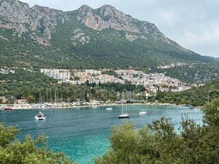 Ships and boats on the coastline in Antalya, Turkey with mountains and village in the background