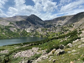 Panoramic view of mountains during a hike in Colorado with a lake and rocks during summer
