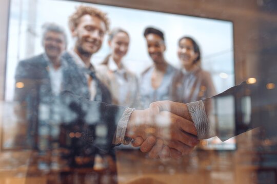 Hybrid video call with a multicultural business team, combining remote and in-office collaboration on screen.