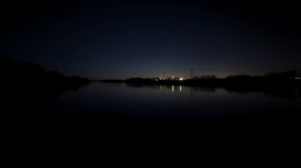 Tranquil lake reflects nighttime lights and sky