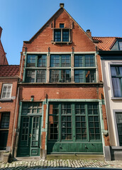Fototapeta premium Charming old townhouse with green doors and red brick walls