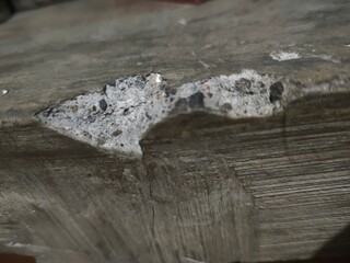 Close-up of damaged concrete surface showing cracks and exposed aggregate. Abstract texture background.