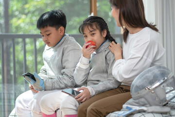 The fencer relaxes by spending time on his cell phone and eating an apple while his mother looks...