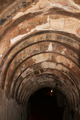 An ancient arched tunnel constructed from weathered bricks and old mortar, revealing eroded...