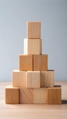 Obraz premium Wooden blocks stacked in a pyramid shape with a few blocks on top displaying a sense of height and balance