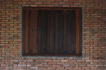 A solid dark wooden window, tightly closed and centered within a meticulously laid reddish-orange...