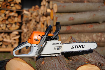 Naklejka premium Powerful chainsaw equipment with a sharp blade cuts through wood, producing sawdust in the forest