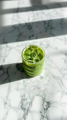 Refreshing Iced Green Drink on a White Marble Surface with Sunlight

