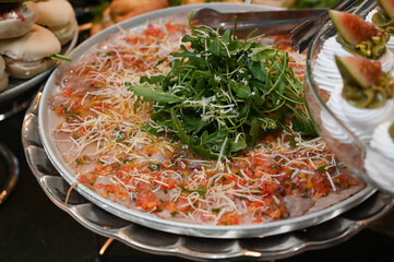 carpaccio , thin beef carpaccio with arugula and parmesan, gourmet meat appetizer with vinaigrette topping, elegant carpaccio platter served cold for events

