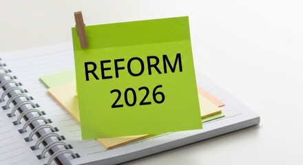 Green sticky note with REFORM 2026 text clipped to a notebook Planning
