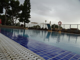 Resort poolside view with lounge chairs and cloudy sky in Mallorca