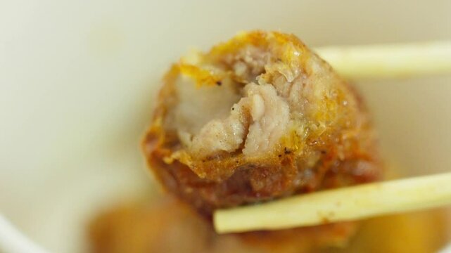 A crispy Fujian-style five-spice meat roll is lifted with chopsticks&mdash;showing golden exterior and flavorful filling, capturing tactile texture and the savory essence of traditional Southern Chinese sna