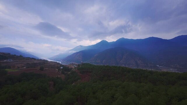 A panoramic view overlooking Tiger Leaping Gorge in Shangri-La captures forested slopes, a lush river valley, and distant snowy mountains&mdash;highlighting natural depth, atmospheric light, and the tranqui