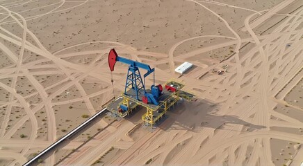 Aerial view of oil pump jack in desert landscape with tire tracks and small white building - Powered by Adobe